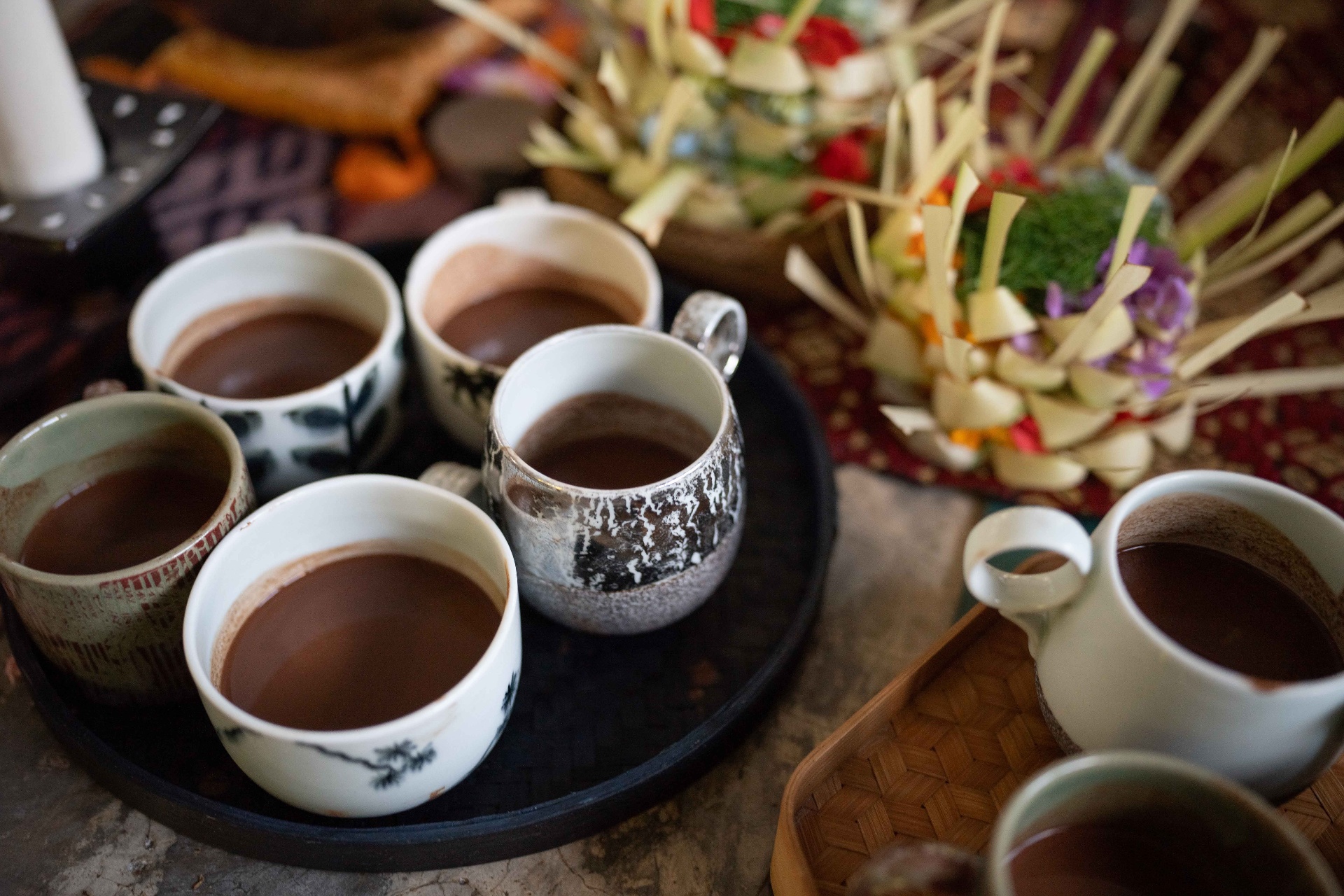 Hand-painted ceremonial cups filled with cacao beside woven offerings